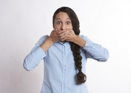 woman covering mouth with wide, excited eyes
