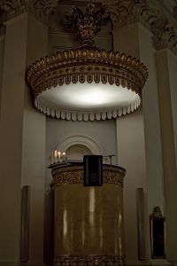 tall pulpit with lighted, round sound board above it