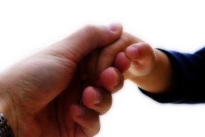 Adult hand holding a child's hand
