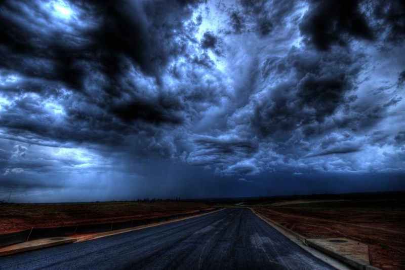 dark storm clouds at night over a paved road without any structures or trees around