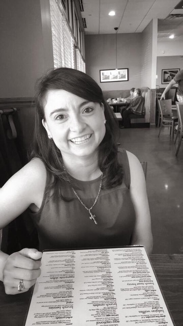 Lisa Lopez smiling, sitting at a table in a restaurant, with a menu in front of her
