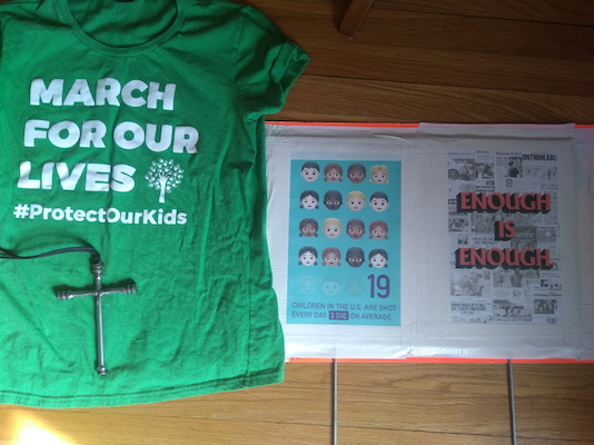 The author’s sign and shirt for March for Our Lives. The Cross in both is made from parts of an AK47.