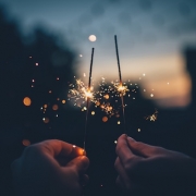 twilight with two hands holding lit sparklers