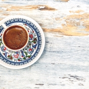dark coffee in small cup with saucer decorated with flowers on a wooden table top, looking from the top