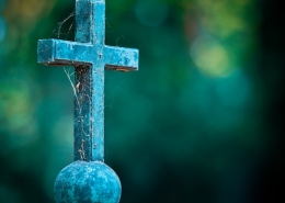 stone cross on ball with spiderwebs