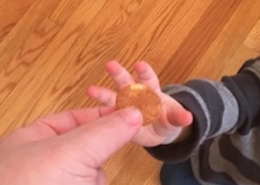 An adult hand handing a Nilla Wafer to a child's hand