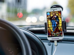 Stained glass Jesus on a phone screen, pointing to app store